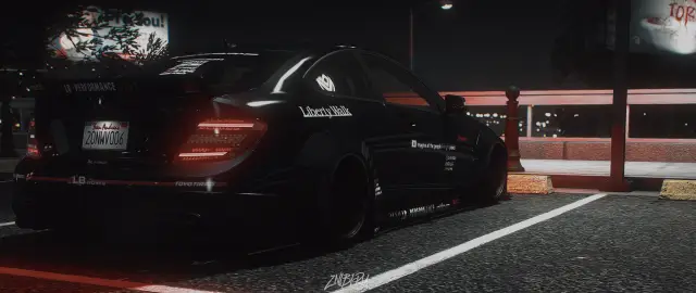 Widebody saloon parked under neon at night